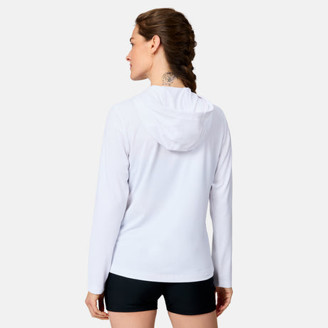 A woman with a braided hairstyle faces away, wearing the Free Country Women's SunFree Full Zip UPF Sunshirt in white and black shorts, set against a plain white background.