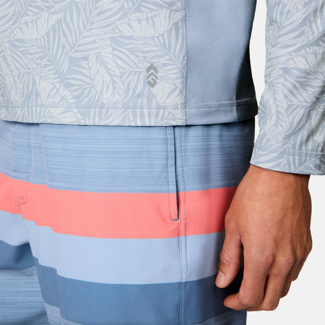 A person wearing the Free Country Men's SunFree UPF Printed Hoodie in light blue; only the torso and right hand are visible.