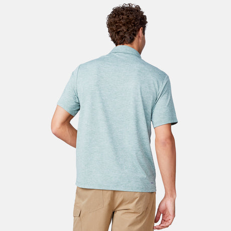 [Miguel is 6'2" wearing a size Medium.] Man wearing Free Country Men's SunFree UPF Polo Shirt in Basil, size M, made from anti-odor, breathable lightweight recycled polyester performance fabric featuring a classic active fit, styled with black shorts #color_basil