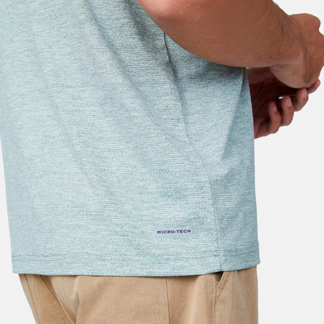 [Miguel is 6'2" wearing a size Medium.] Man wearing Free Country Men's SunFree UPF Polo Shirt in Basil, size M, made from anti-odor, breathable lightweight recycled polyester performance fabric featuring a classic active fit, styled with black shorts #color_basil