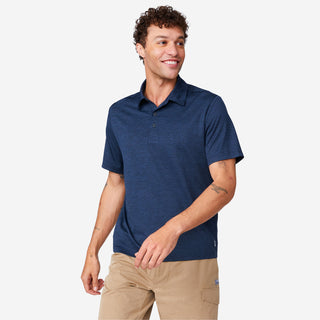 [Miguel is 6'2" wearing a size Medium.] Man wearing Free Country Men's SunFree UPF Polo Shirt in Navy, size M, made from anti-odor, breathable lightweight recycled polyester performance fabric featuring a classic active fit, styled with black shorts #color_navy