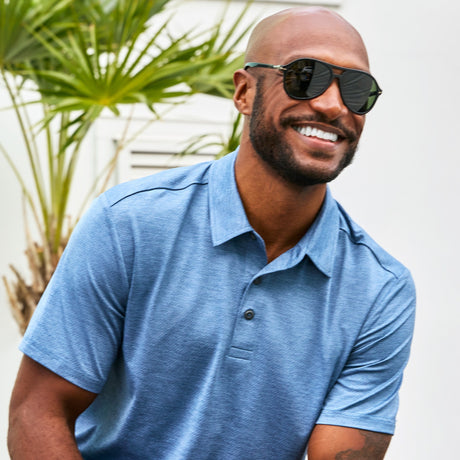 Man wearing Free Country Men's SunFree UPF Polo Shirt in Wave, size M, made from anti-odor, breathable lightweight recycled polyester performance fabric featuring a classic active fit