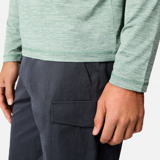 A person wearing a light green Free Country Men's Textured SunFree UPF Hoodie and dark gray cargo pants; the image shows their torso, left arm, and right hand.