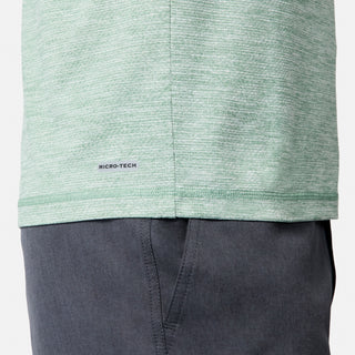 Close-up of a person wearing the Free Country Men's Textured SunFree UPF Hoodie in light green and dark gray pants. The hoodie’s fabric provides moisture wicking and UPF 50+ sun protection for all-day comfort. Only part of the torso and upper leg is visible.