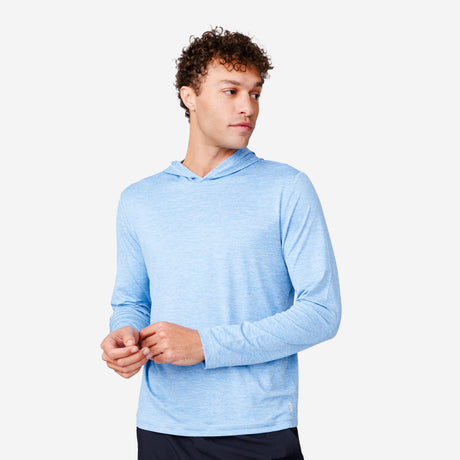 A man with curly hair wears the Free Country Men's Textured SunFree UPF Hoodie in light blue and dark pants, standing against a white background and looking to his left.