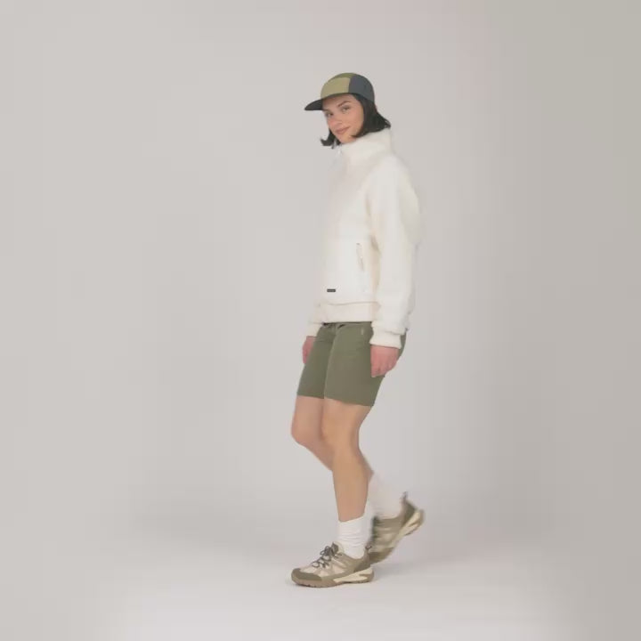 Model wearing the Women's Sedona Bonded Sherpa Jacket in cream, worn with a cap and olive shorts