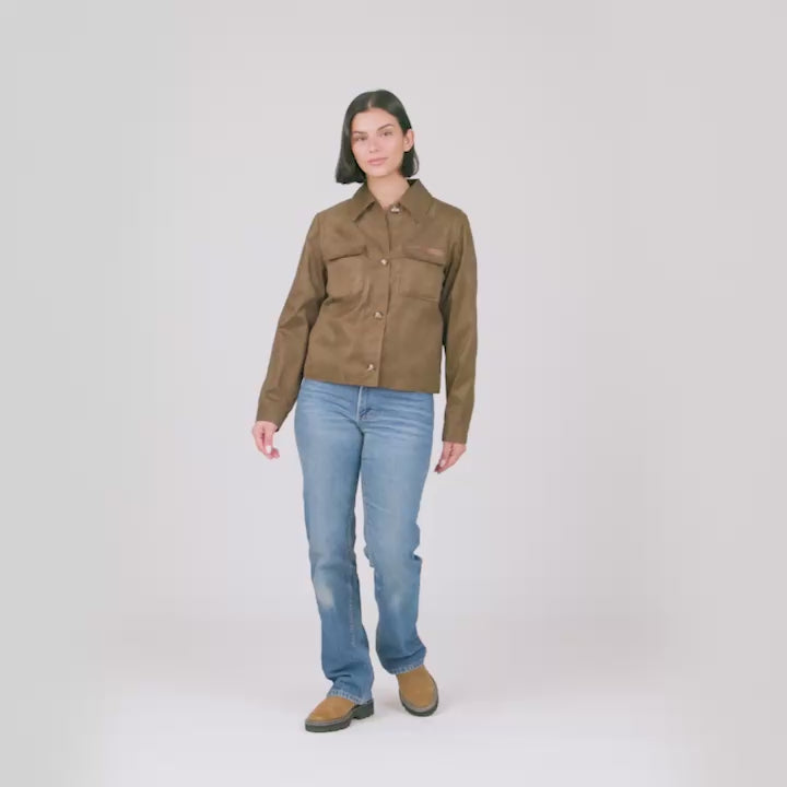 A female model in blue jeans and a brown suede-like Free Country jacket models the different features of the jacket.