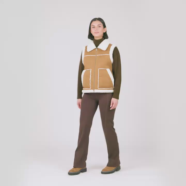 Model wearing the Women's Faux-Suede Shearling Reversible Vest in tan shearling with brown trim