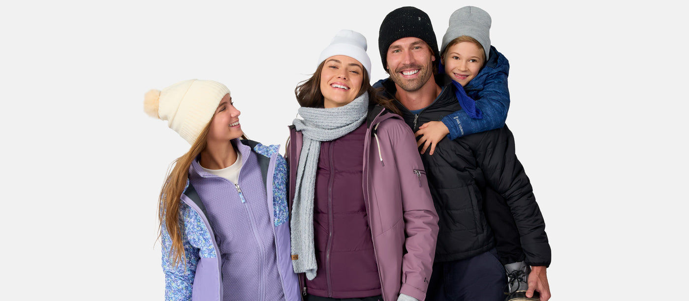 Family of four wearing winter clothing on a white background