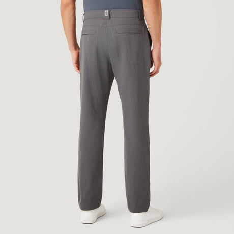 [Model is wearing a size Medium.] Man wearing Free Country Men's Nylon Stretch Casual Pant in Charcoal, size M, made from comfortable stretch performance fabric featuring a water repellent finish, articulated knee, coin pocket, and gusset at crotch, styled with a grey t shirt and white shoes #color_charcoal