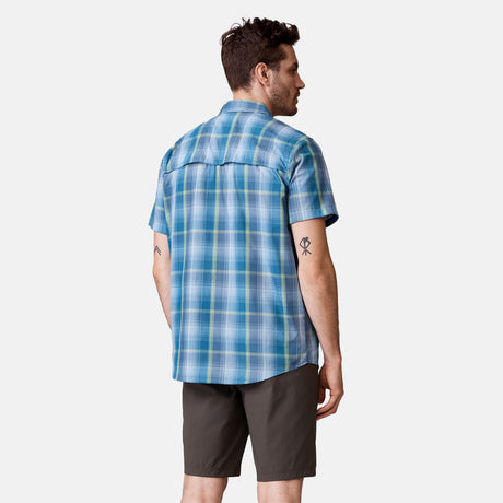 [Will is 6'2" wearing a size Medium.] Man is wearing Free Country Men's Excursion Short Sleeve Poplin Shirt in Denim Trails Plaid, size M, made from lightweight moisture wicking polyester fabric featuring vent at the back, full button down front, and a stand collar, styled with brown shorts #color_denim-trails