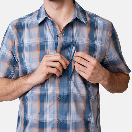 [Will is 6'2" wearing a size Medium.] Man is wearing Men's Excursion Short Sleeve Poplin Shirt in Dried Sage Plaid, size M, made from lightweight moisture wicking polyester fabric featuring vent at the back, full button down front, and a stand collar, styled with brown shorts #color_dried-sage
