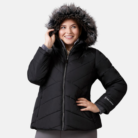 [Lola is 5'10.5" wearing a size 1X.] Woman wearing Free Country Women's Brisk II Parka Jacket in black with a full front zipper opening, soft lining, attached hood with faux fur trim, recycled polyester fill, and water resistant and wind resistant stretch performance fabric, light grey background. Perfect women’s  jacket for fall weather.