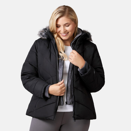 [Lola is 5'10.5" wearing a size 1X.] Woman wearing Free Country Women's Brisk II Parka Jacket in black with a full front zipper opening, soft lining, attached hood with faux fur trim, recycled polyester fill, and water resistant and wind resistant stretch performance fabric, light grey background. Perfect women’s  jacket for fall weather.