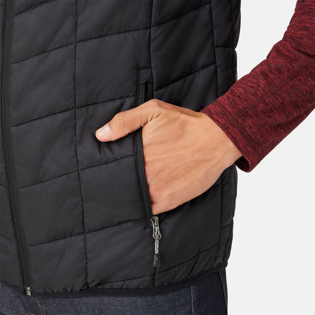 [Model is wearing a size Medium.] Man wearing the Free Country Men's FreeCycle® Stimson Puffer Vest in black, featuring quilted design, REPREVE® poly fill, and a vertical zip, layered over a burgundy long-sleeve shirt with dark jeans.