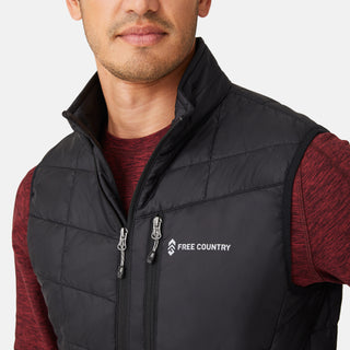 [Model is wearing a size Medium.] Man wearing the Free Country Men's FreeCycle® Stimson Puffer Vest in black, featuring quilted design, REPREVE® poly fill, and a vertical zip, layered over a burgundy long-sleeve shirt with dark jeans.