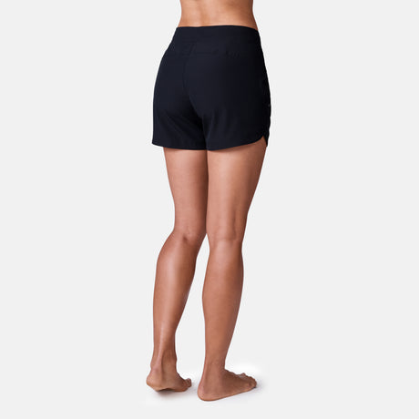 [Model is 5’9” wearing a size Small.] Woman wearing Free Country Women's 5" Bermuda Board Short in Black, size S, made from quick drying UPF stretch performance fabric featuring a fly front zipper closure with a drawcord and two front pockets 